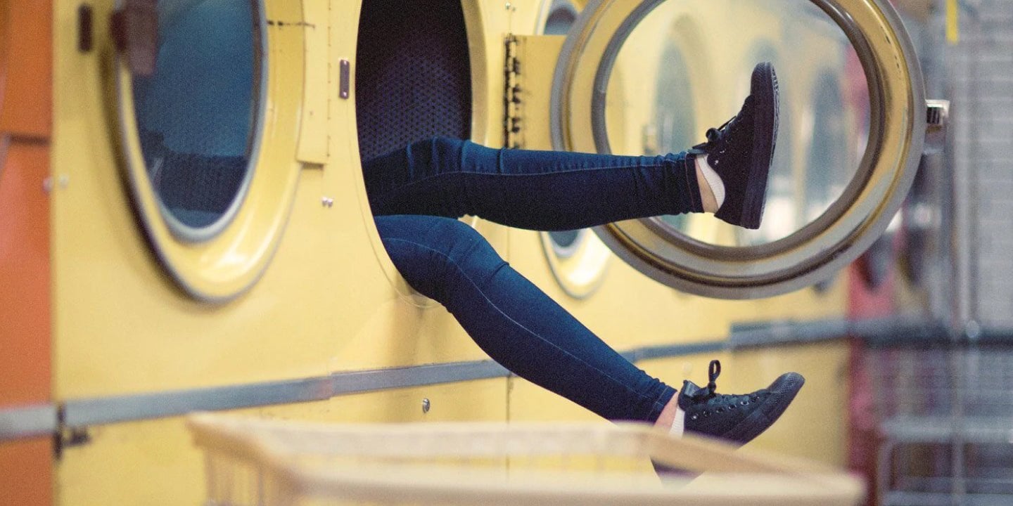 A person in a washing machine with their legs hanging out