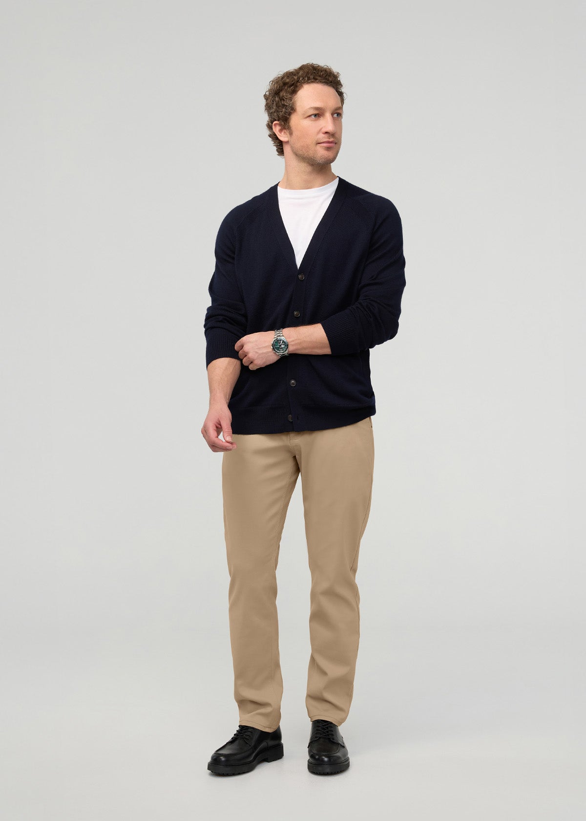 Man wearing desert khaki relaxed taper trousers with a navy cardigan and white shirt.