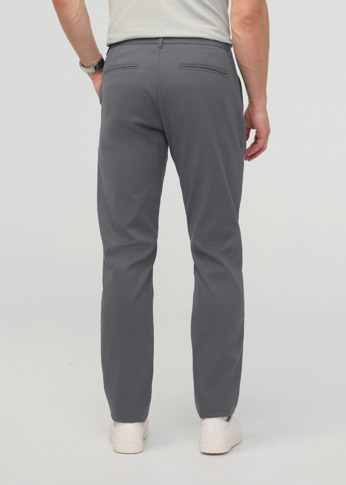 Man wearing gray relaxed taper trousers with back pockets, paired with cream sneakers.
