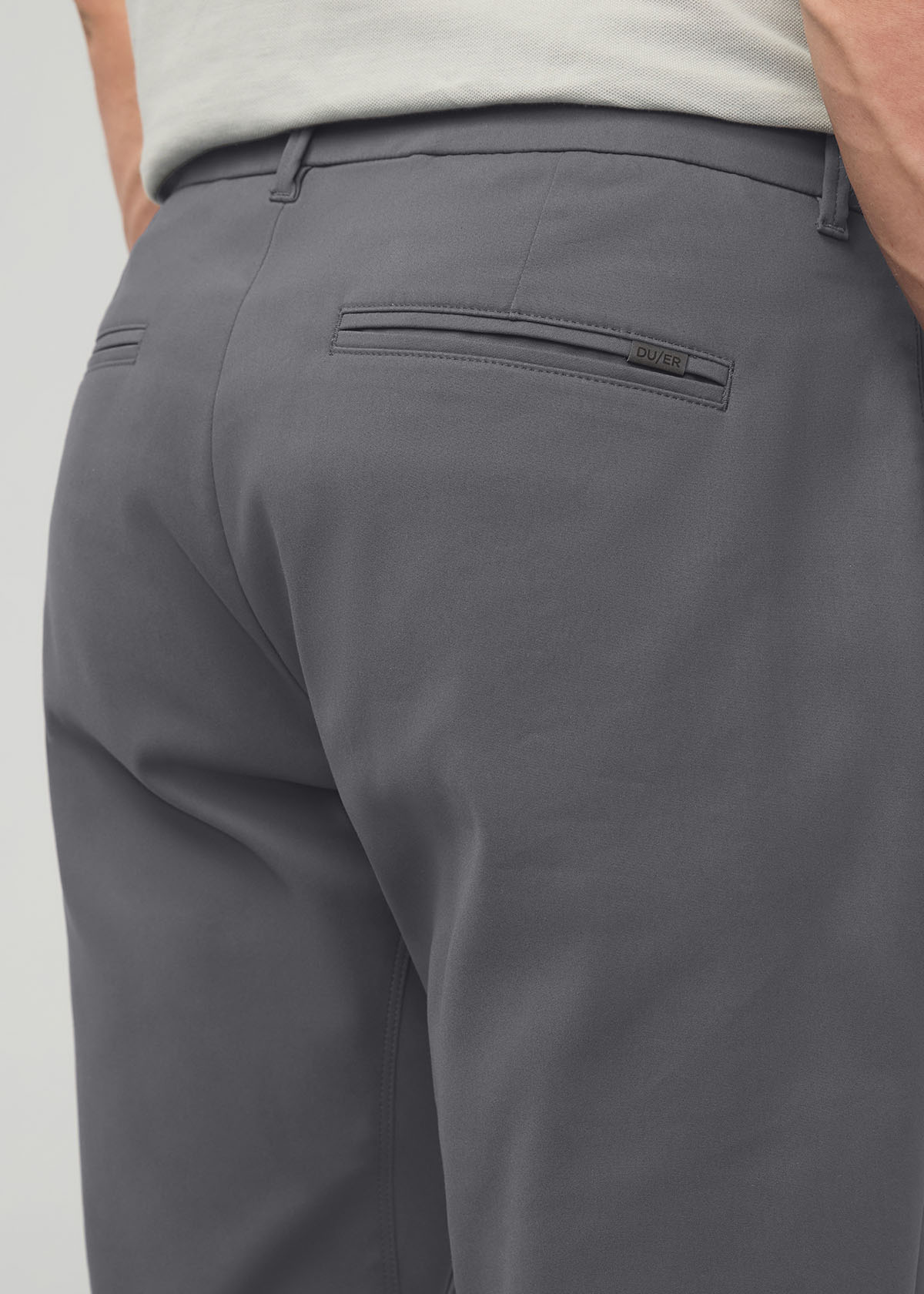 Gray relaxed taper trouser with back pocket and tapered leg, shown from rear on model wearing light top.