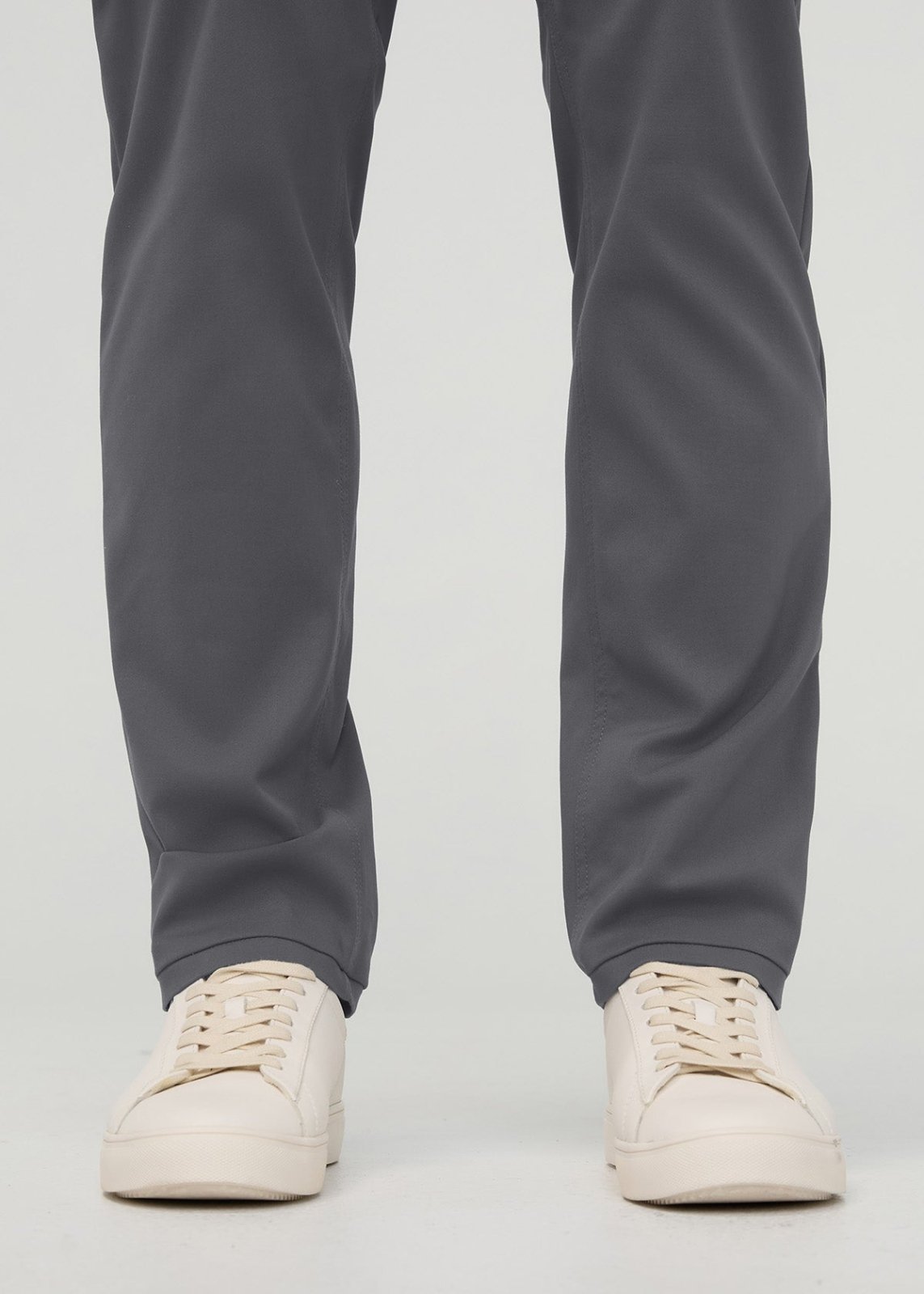 Gray relaxed taper trousers with tapered ankles, paired with cream lace-up sneakers.