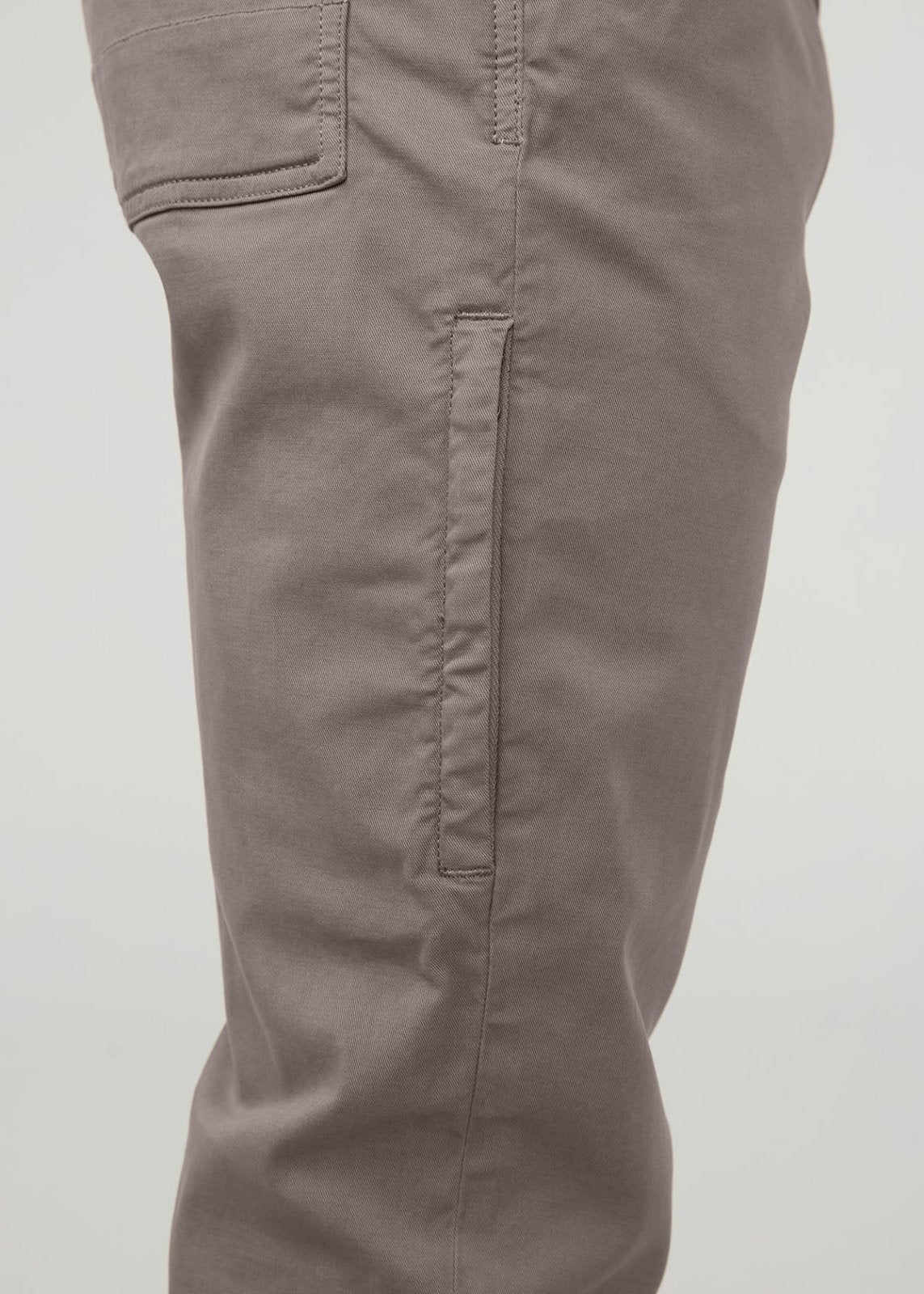 Stone-colored cargo pants with side pockets and vertical seam details on the leg.