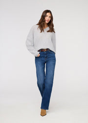 Woman wearing a gray sweater and blue jeans on a white background