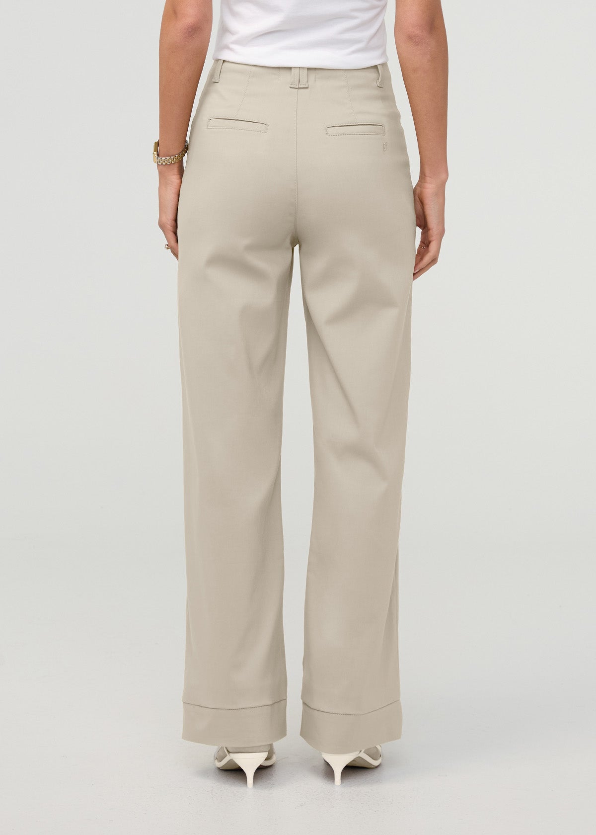 Sandstone high-rise trousers with back pockets and cuffed ankles, shown from behind on a model.