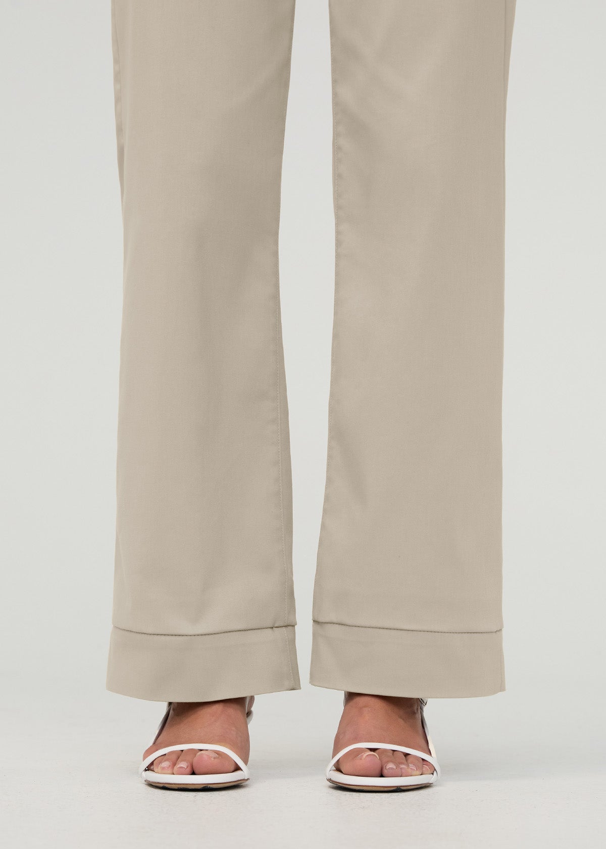 Sandstone high-rise trousers with rolled cuffs, shown from waist down with white slide sandals.