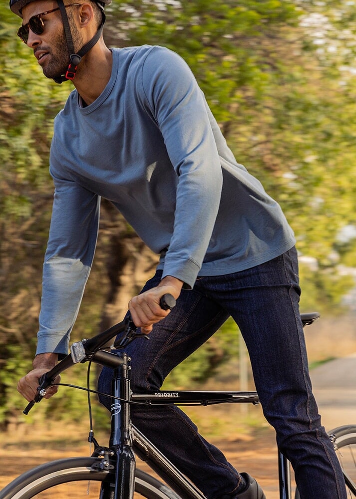 man wearing blue midweight long sleeve tee sleeve with jeans on a bike