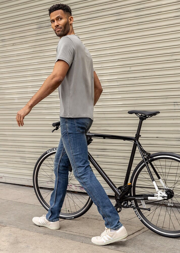 mens medium wash slim fit stretch jeans walking outside with a bicycle