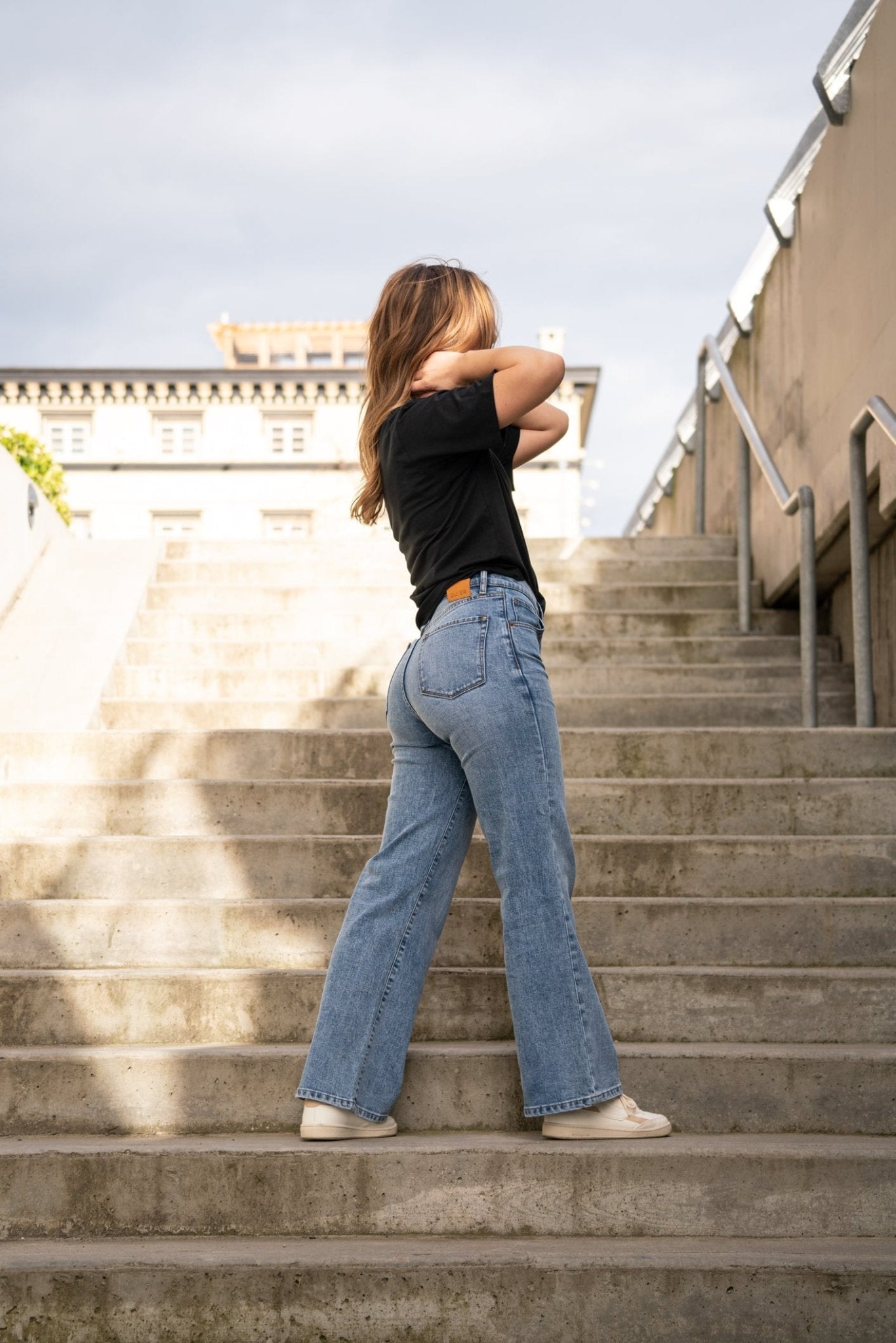 woman wearing High Rise Wide Leg Blue Stretch Jeans Full Body posing on concrete stairs