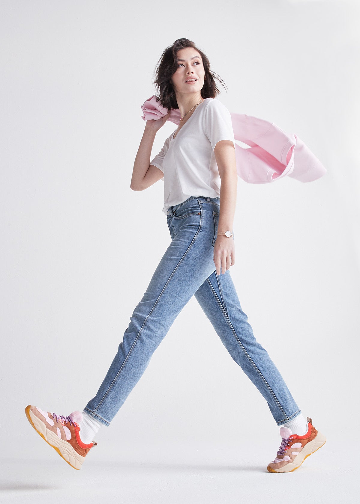 woman wearing vintage blue high rise straight stretch jeans holding a pink sweater
